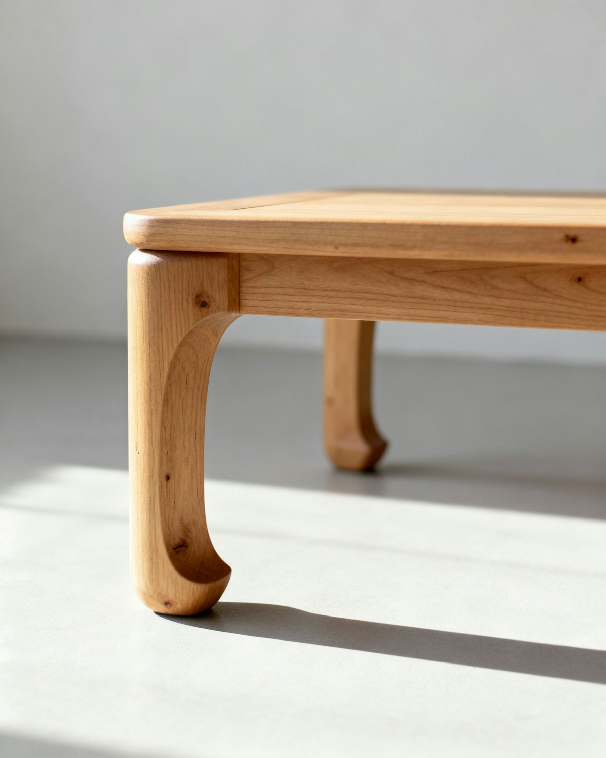 Close-up of a curved wooden table leg, the natural grain running through a smooth shaped joint.
